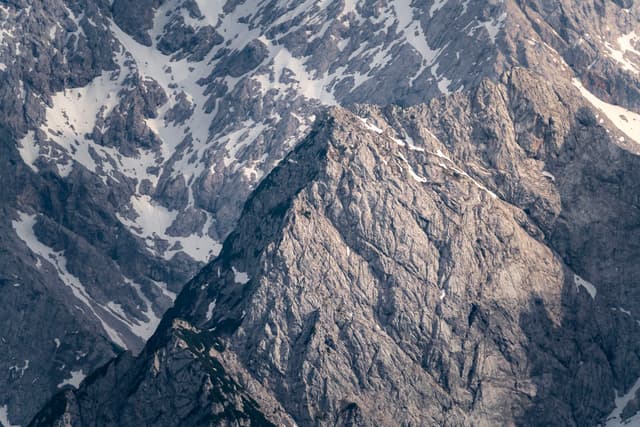 Sharp rocky mountain peak rising amid surrounding snow-dusted ridges