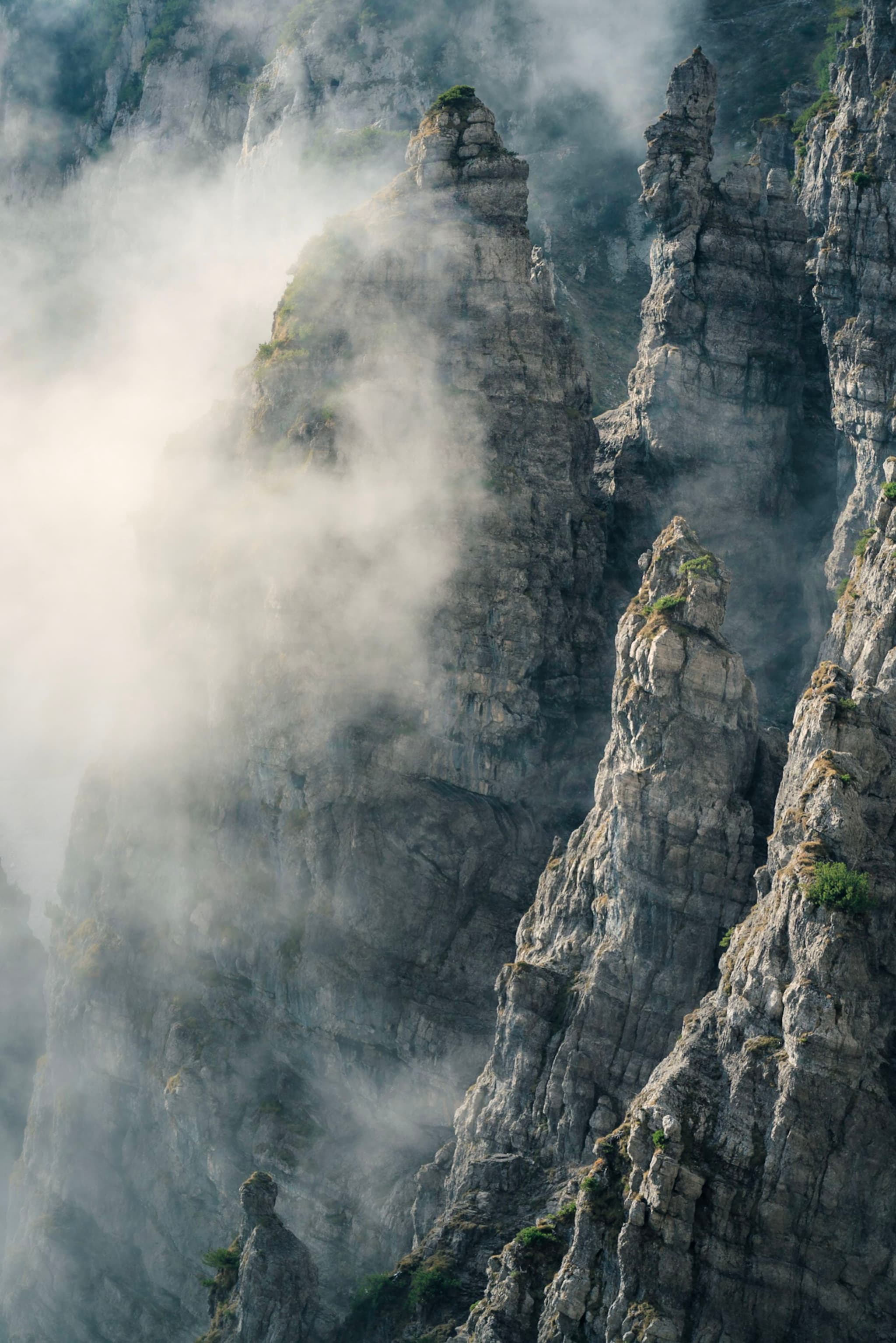 Jagged, rocky peaks shrouded in mist, creating a dramatic and mysterious atmosphere