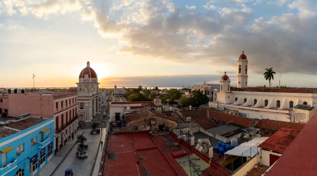 Panoramic view over colorful colonial rooftops and church towers in a coastal Cuban city at sunset
