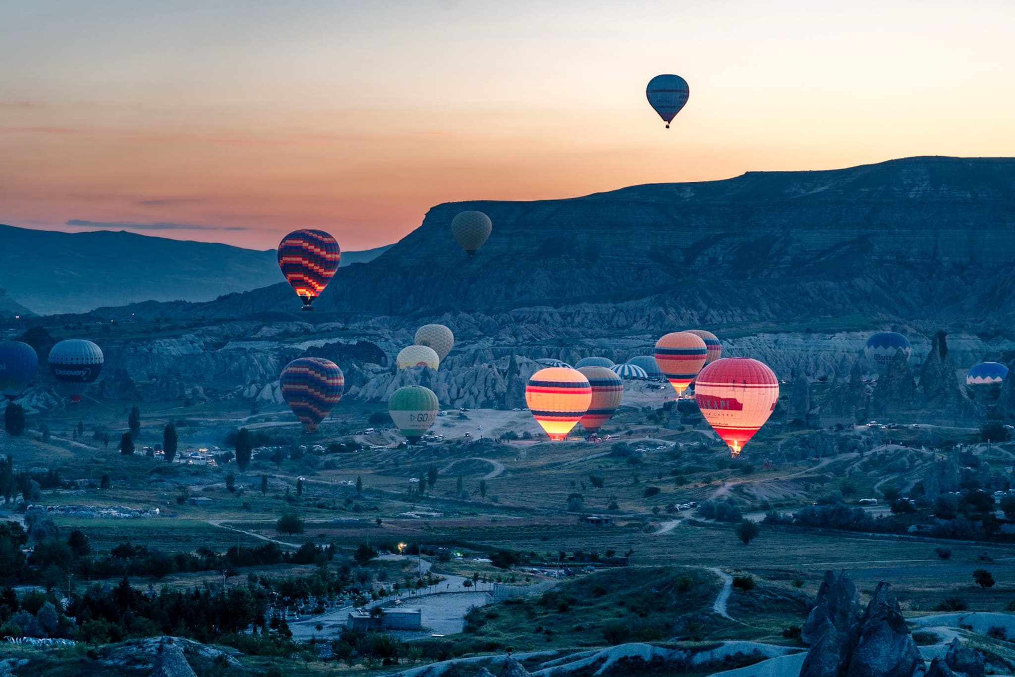 Hot air balloons floating over a scenic landscape at sunrise, with rolling hills and a clear sky in the background