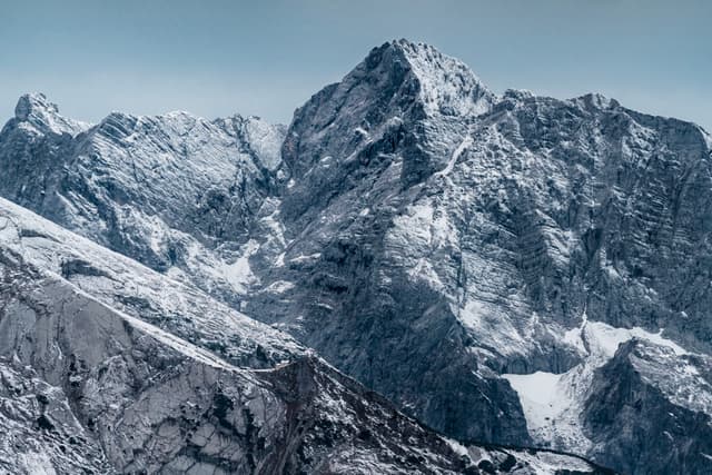 Jagged snow-covered mountain peaks under a pale blue sky