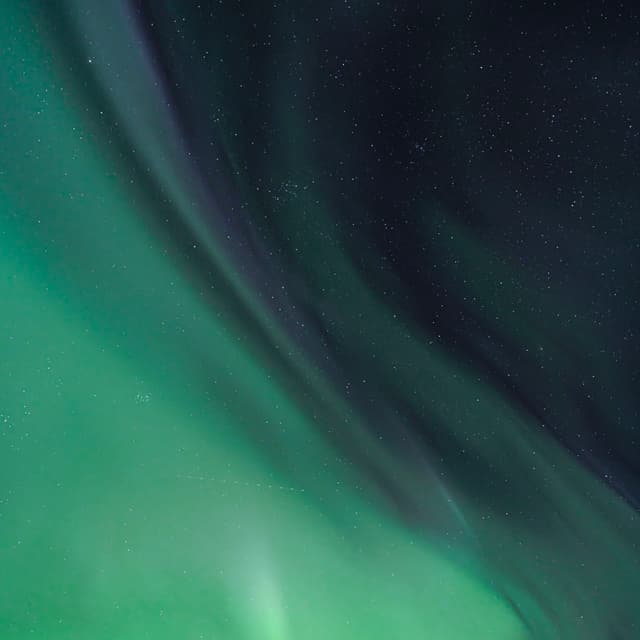 Green aurora borealis curtains sweeping across a starry night sky