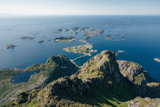 Aerial view of a coastal landscape with rugged mountains, small islands, and deep blue sea under a clear sky