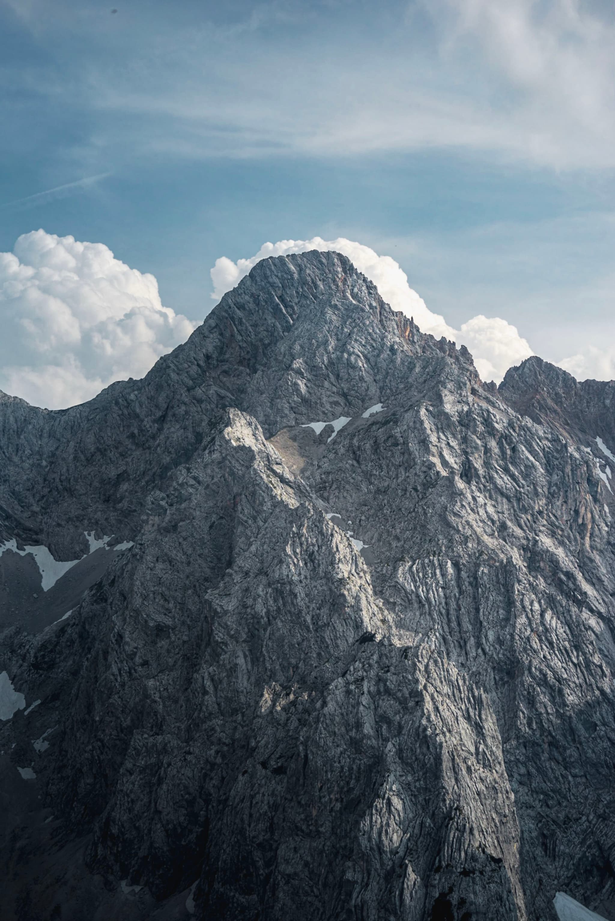 Towering rocky mountain peak under a partly cloudy blue sky