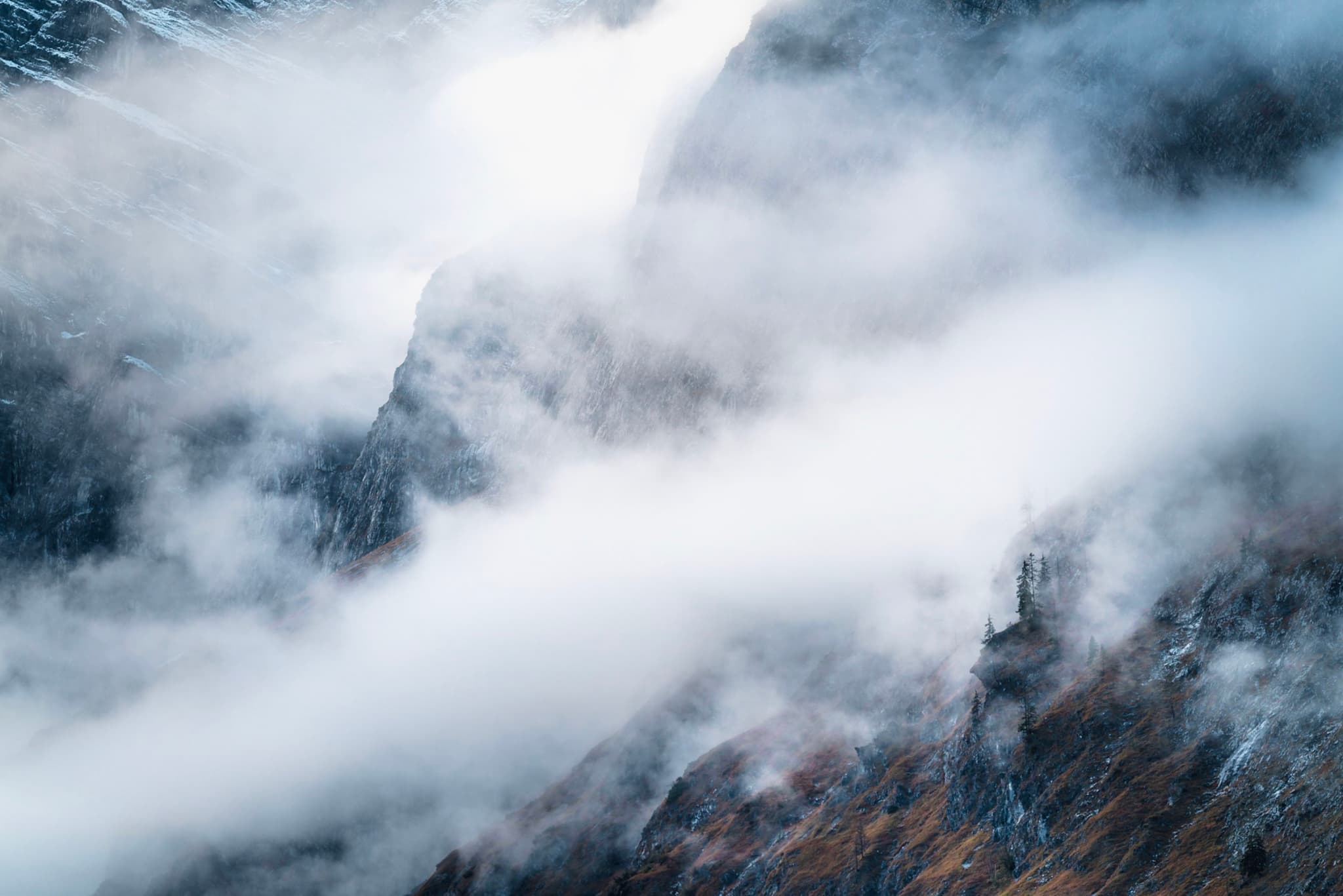 Jagged mountain slopes partly obscured by drifting white mist and low clouds