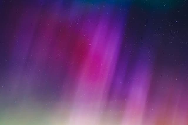 Vibrant streaks of purple, pink, and blue light blend together against a dark background, resembling an abstract aurora