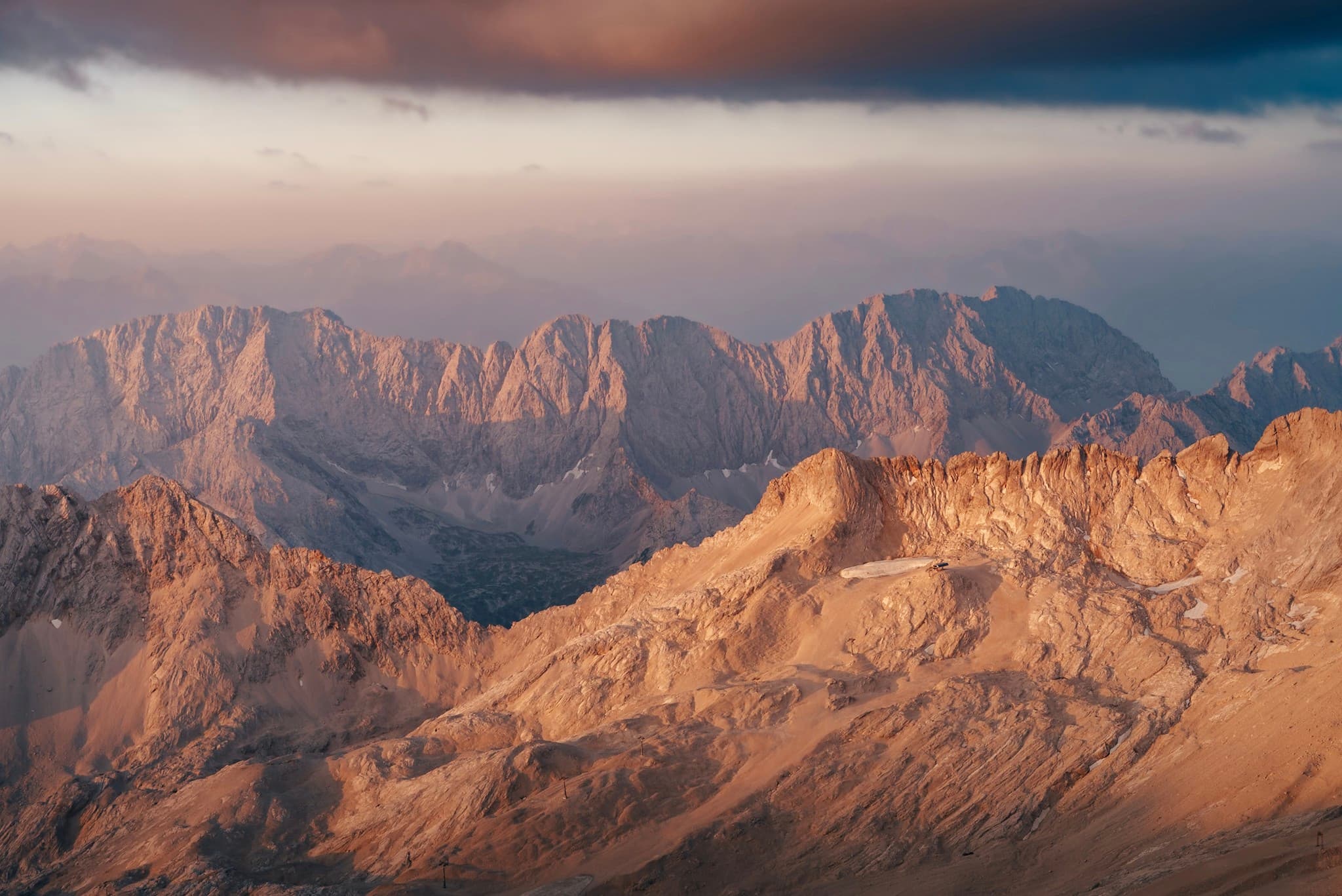 Sunlit mountain ridges glowing in warm evening light beneath a dramatic cloudy sky