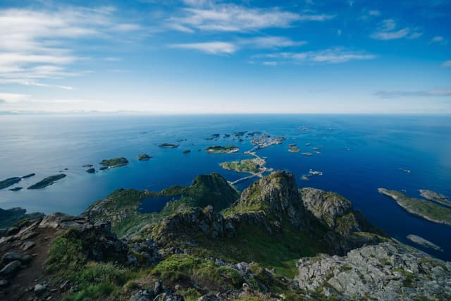 A breathtaking view of a coastal landscape with rocky islands scattered across a deep blue sea, under a clear sky