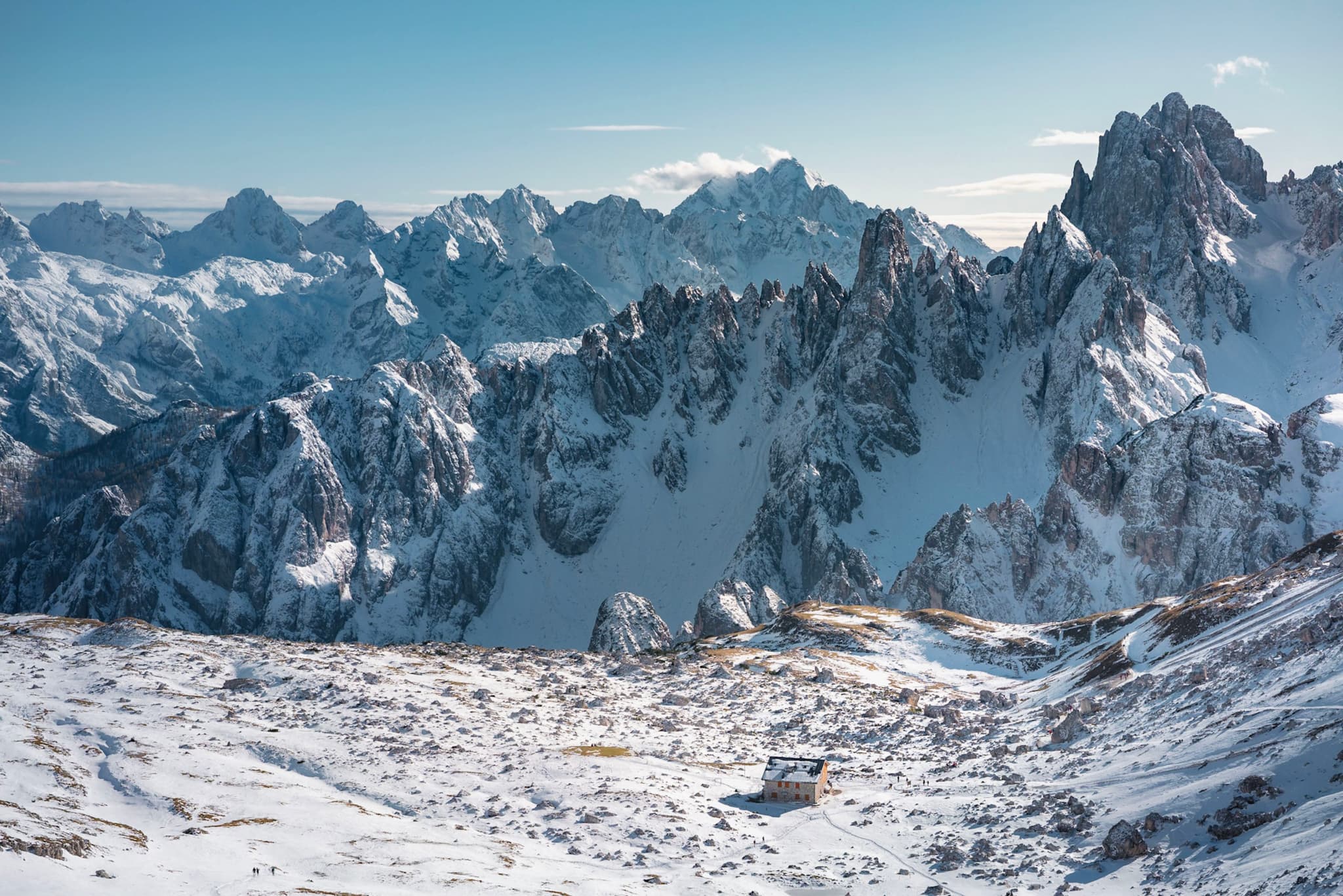 snow-covered mountain range with jagged rocky peaks under a clear blue sky