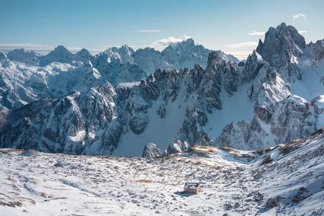 snow-covered mountain range with jagged rocky peaks under a clear blue sky