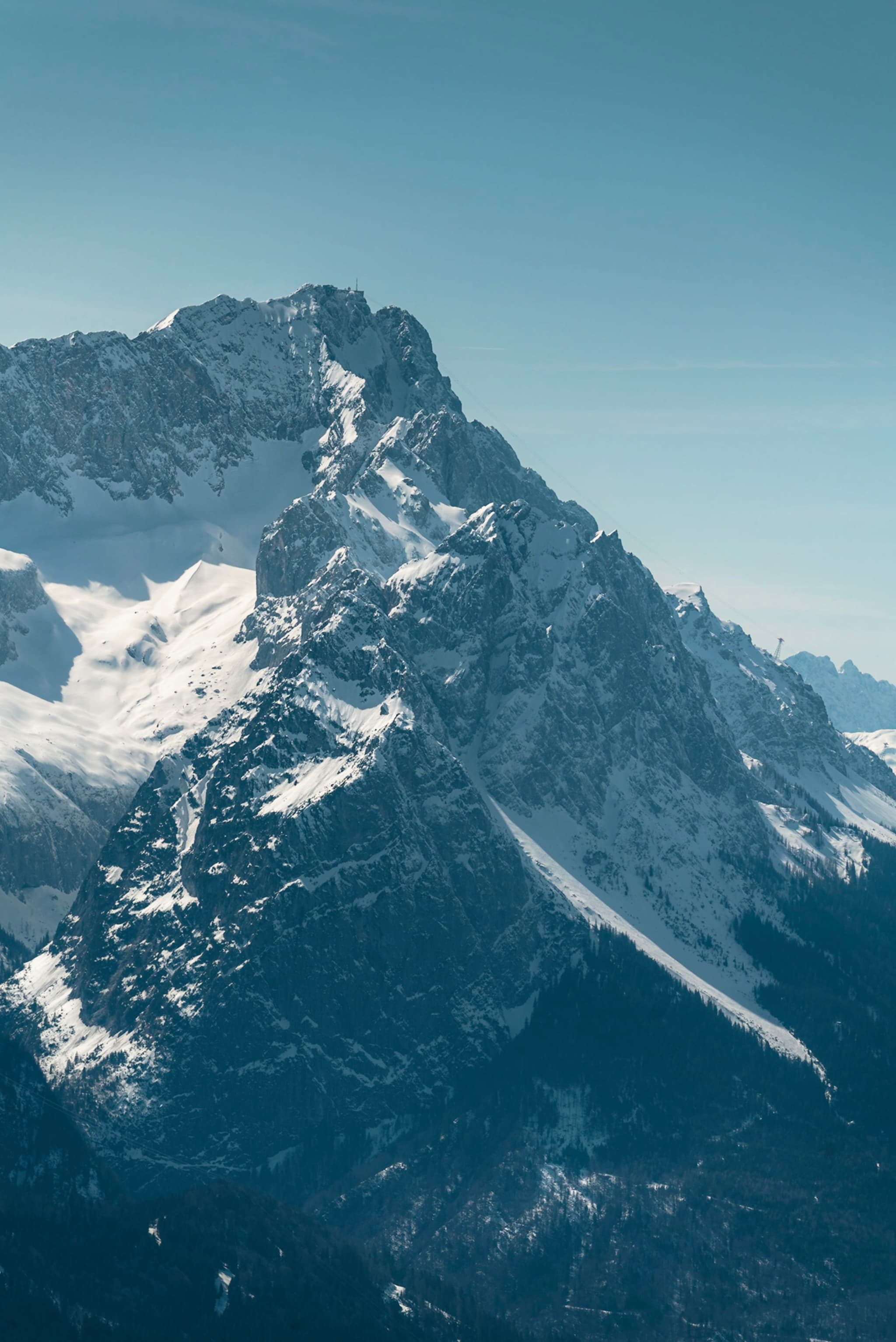 snow-covered jagged mountain peak rising sharply against a clear blue sky