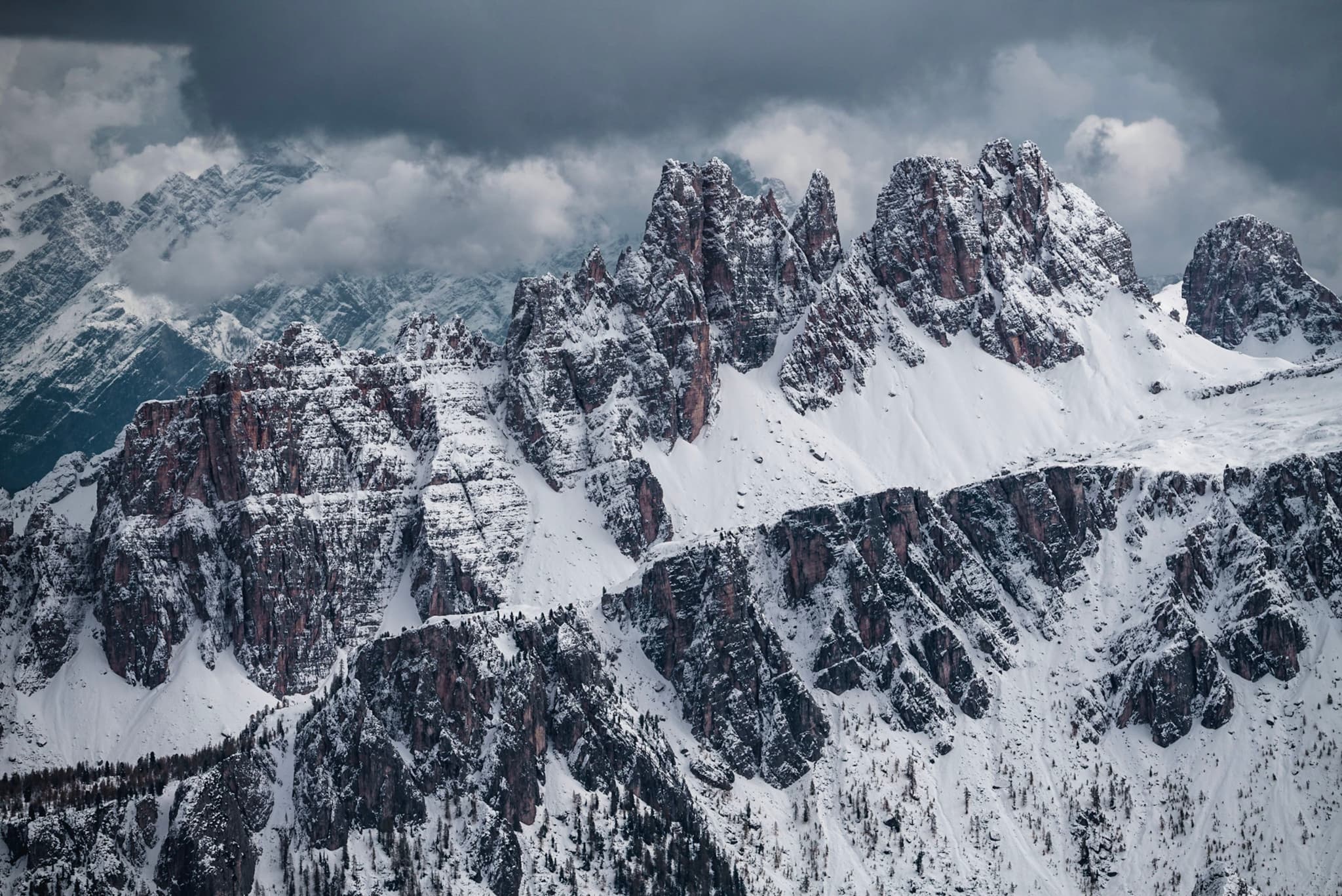 Jagged snow-covered mountain peaks under heavy clouds in a dramatic alpine landscape