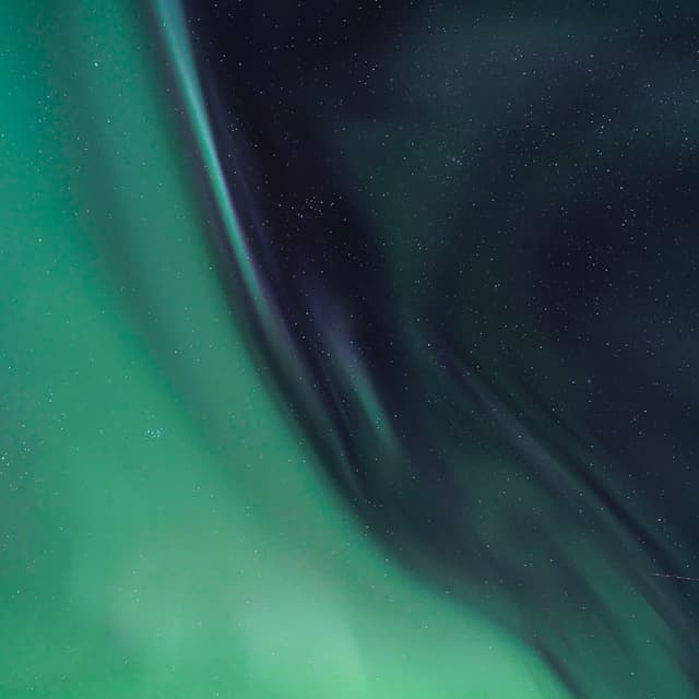 Abstract close-up of soft green and dark blue aurora lights blending in the night sky
