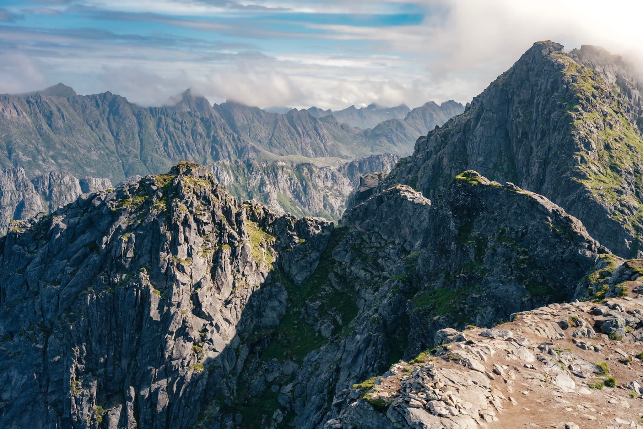 A rugged mountain range with sharp peaks under a partly cloudy sky