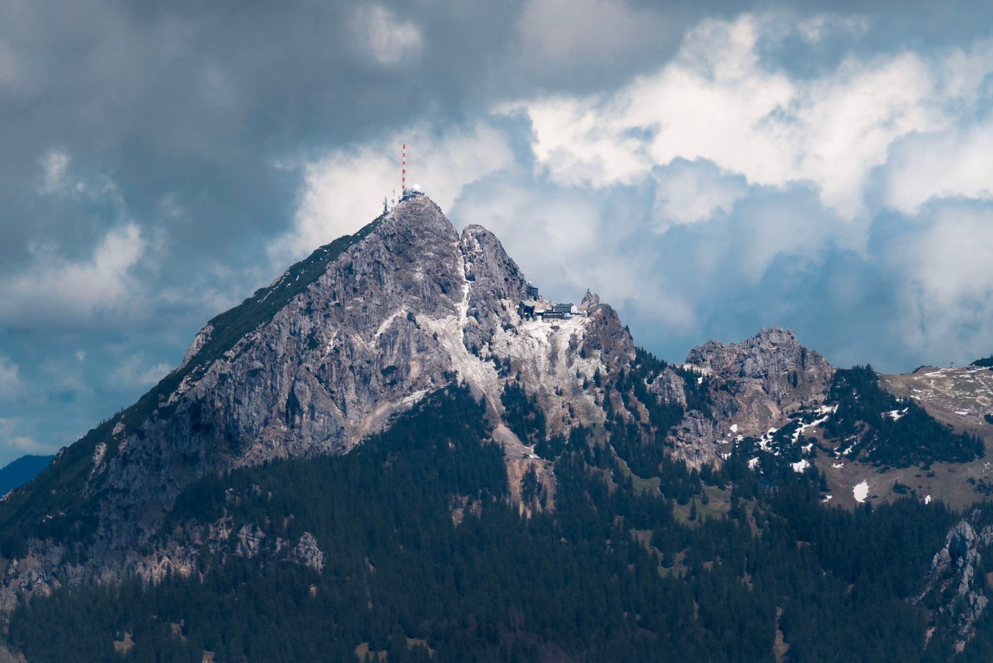 Jagged, snow-dusted mountain peak rising beneath dramatic clouds