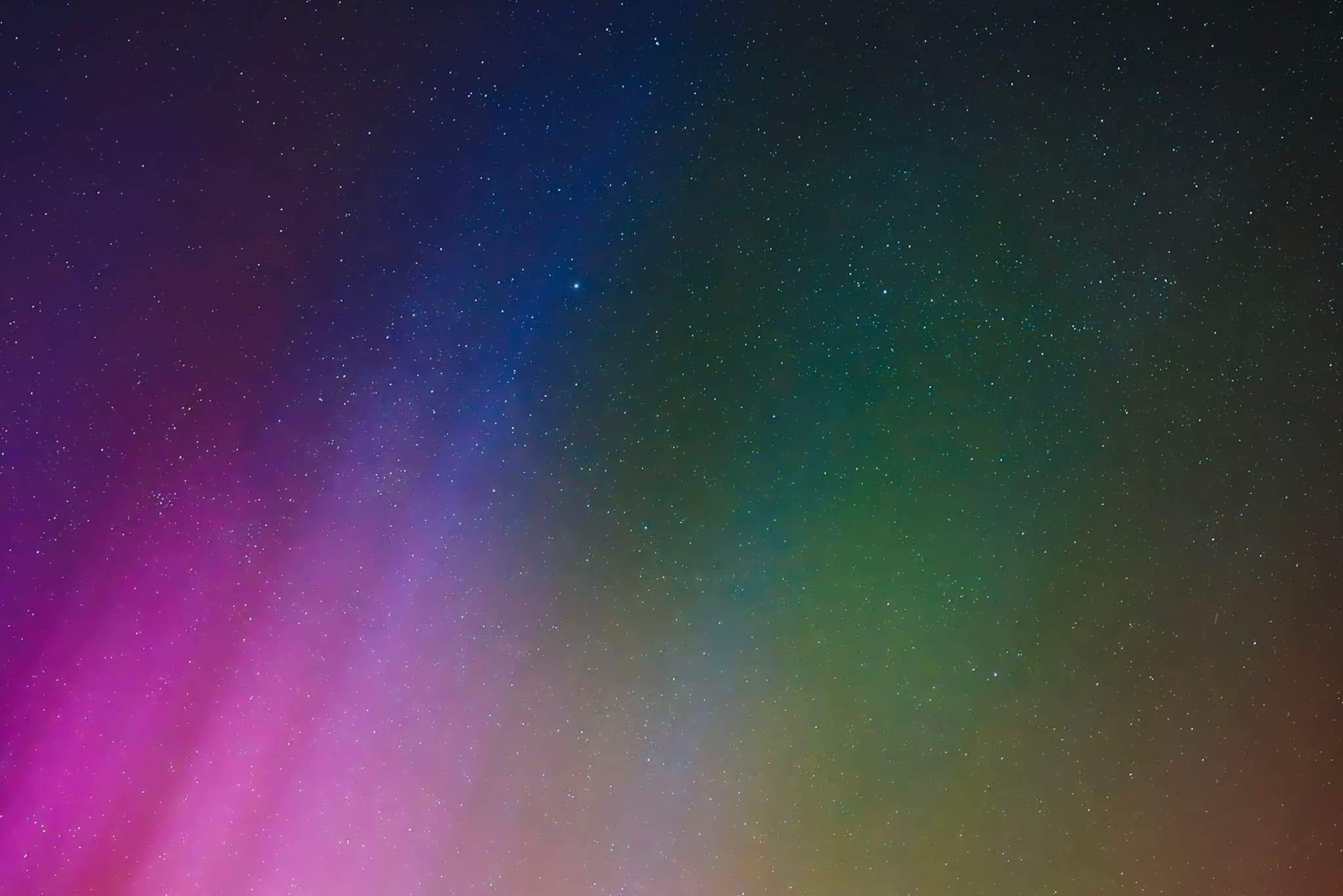 A colorful aurora with shades of pink, green, and blue against a dark night sky