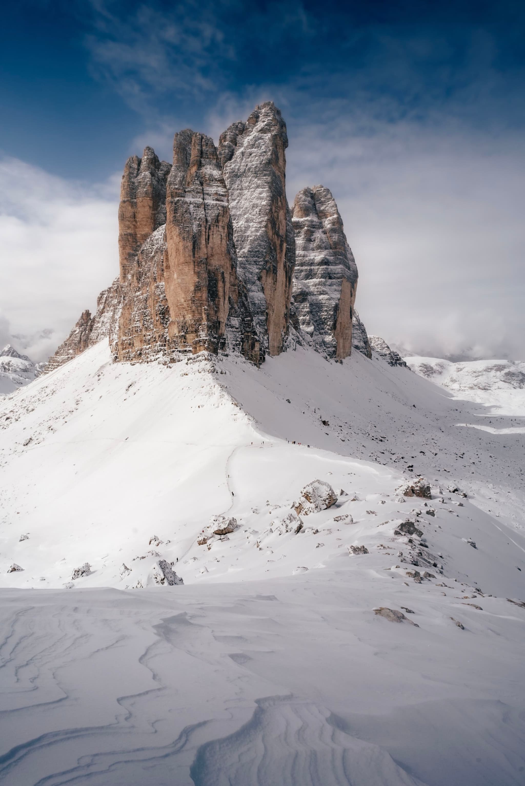 A snow-covered mountain landscape with towering rock formations under a partly cloudy sky