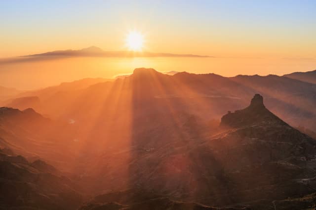 A breathtaking sunrise over a mountainous landscape, with sun rays illuminating the misty valleys and peaks