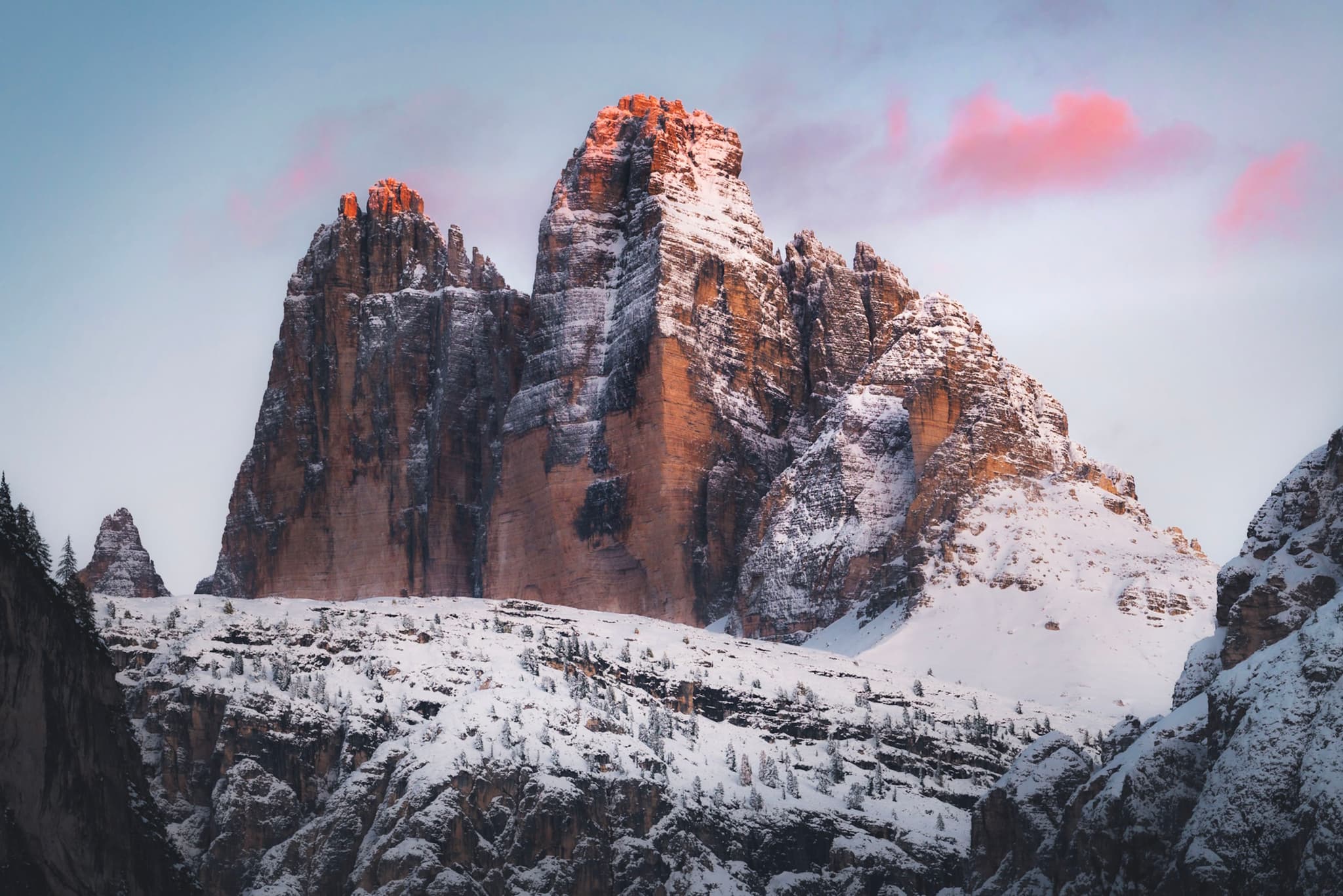 towering snow-covered mountain peaks glowing with warm light under a pastel pink and blue sky